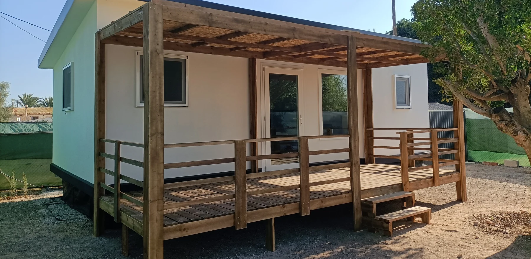 Porche de madera con cubierta, barandillas y escalones