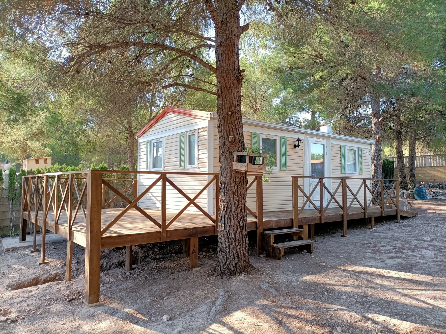 Terraza de madera con barandillas junto a una casa móvil